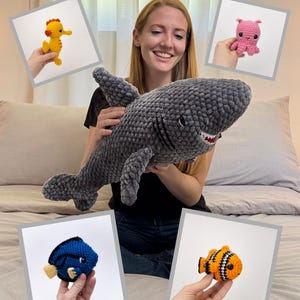 May include: A woman holding a large gray crochet shark, with four smaller crochet sea creatures displayed around her: a yellow seahorse, a pink octopus, a blue fish, and an orange and black fish. The text "5 CROCHET PATTERN PACK:" is at the top.
