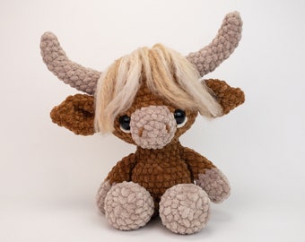 Peut inclure: Un animal en peluche crocheté marron avec une crinière blanche moelleuse et de grands yeux bruns. L'animal a un long museau et de petites oreilles arrondies.