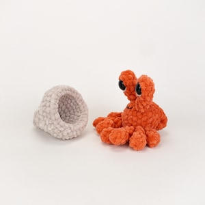 Może przedstawiać: Ręcznie robiony pomarańczowy krab z czarnymi oczami i białą skorupą.