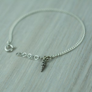 May include: A silver chain bracelet with a small seashell charm.