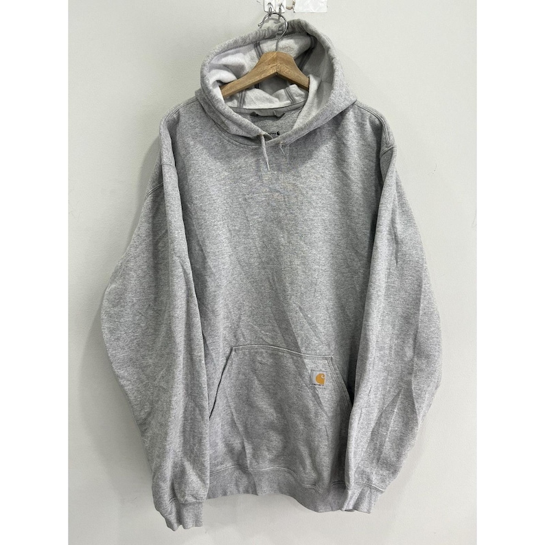 May include: A grey hooded sweatshirt with a front pocket and a small yellow Carhartt logo on the pocket.