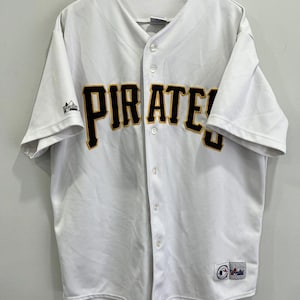 May include: White baseball jersey with the word "PIRATES" in black and gold lettering across the chest. The jersey has a button-up front and short sleeves. A team logo is visible on the left chest and lower right.