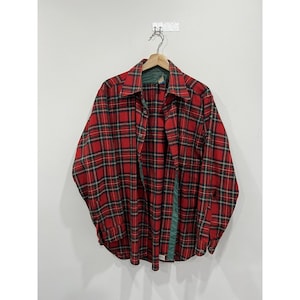 May include: Red and green plaid flannel shirt with long sleeves and a button-up front.