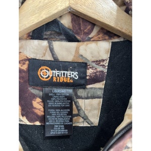 May include: A black and brown camouflage jacket with a black label that reads "Outfitters Ridge" and includes size and care instructions.