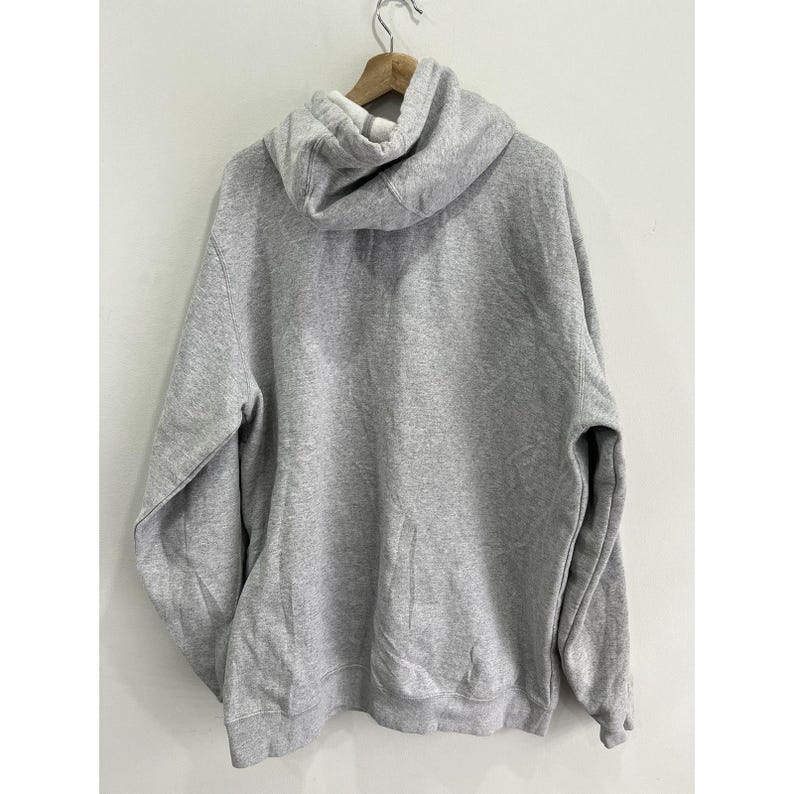 May include: A grey hooded sweatshirt with a pouch pocket. The sweatshirt has long sleeves and a drawstring hood.