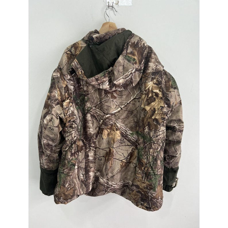 May include: Camouflage jacket with a hood and zipper closure. The jacket is made of a water-resistant material and has a drawstring hood.