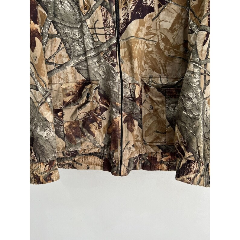 May include: A camouflage jacket with a zipper closure and two pockets. The jacket is made of a lightweight fabric and has a relaxed fit.