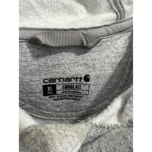May include: Grey Carhartt sweatshirt with a tag that reads "XL Tall Loose Fit Made in Honduras Built to Serve and Protect Hardworking People"
