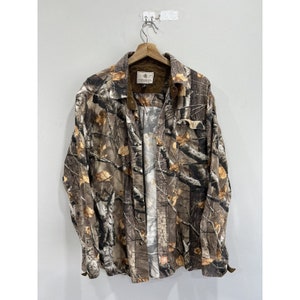 Pu&ograve; includere: Una camicia abbottonata a maniche lunghe con motivo mimetico marrone, beige e bianco, con colletto marrone e un'etichetta marrone sul petto sinistro che dice "Ligonier".