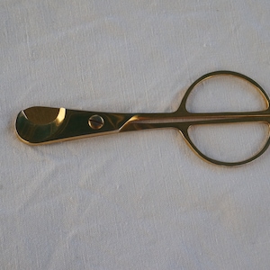 May include: Gold-toned cigar cutter with a round handle and a blade for cutting cigars.