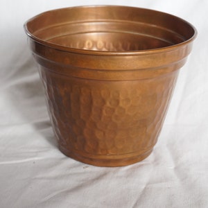 Peut inclure: Un pot en cuivre martelé avec un fond arrondi et un bord légèrement évasé. Le pot est fait de cuivre épais et durable et a un aspect rustique et vieilli.