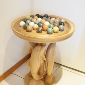 Large solitaire game on stand carved with three dolphins with semi-precious stone balls