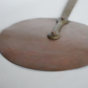 Peut inclure: Une pelle à pizza ronde en cuivre avec un manche en bois. Le manche est doté de deux rivets en laiton.