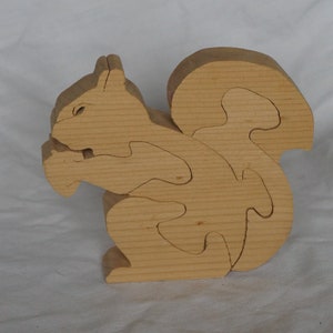 May include: A wooden squirrel puzzle with intricate cutouts. The squirrel is in a sitting position with its tail curled behind it.