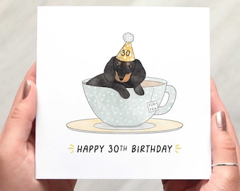 May include: A birthday card featuring a black and brown dachshund wearing a party hat with the number 30. The dog is inside a teacup with a tea bag that says "Fur Tea". The card reads "Happy 30th Birthday".