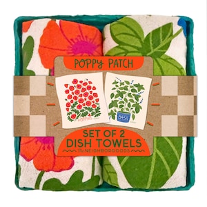 May include: A set of two dish towels in a teal tray. The towels feature floral and botanical designs, including poppies and basil. The packaging reads "Poppy Patch" and "Set of 2 Dish Towels."