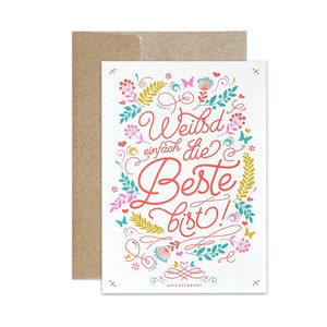 Könnte beinhalten: Eine weiße Karte mit einem floralen Design und dem Text "Weibd' einfach die Beste bist!" in roter und rosa Schrift. Die Karte hat einen braunen Umschlag.