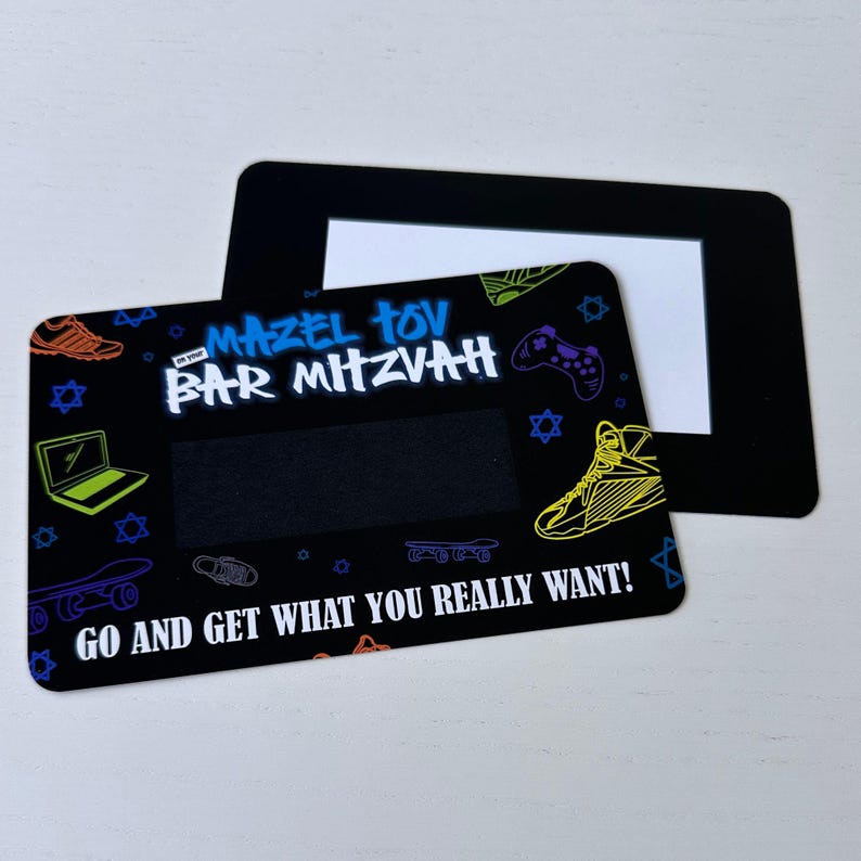 May include: Black and white card with a colourful design featuring a laptop, trainers, skateboards, and a video game controller. The text "Mazel Tov Bar Mitzvah" is in blue and white. The text "Go and get what you really want!" is in white.