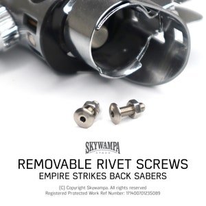 Puede incluir: Dos tornillos de metal plateado con tuercas, utilizados para sujetar piezas de sable láser. Los tornillos están sobre un fondo blanco con el texto "REMOVABLE RIVET SCREWS EMPIRE STRIKES BACK SABERS (C) Copyright Skywampa. All rights reserved Registered Protected Work Ref Number: 171400701235089" debajo.