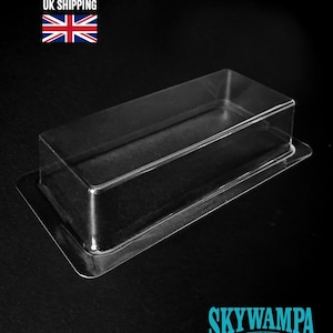 May include: A clear, rectangular plastic blister pack tray with a raised central cavity and a flat, wide border flange. The transparent container is designed for protective packaging and display, featuring a smooth, molded surface throughout.