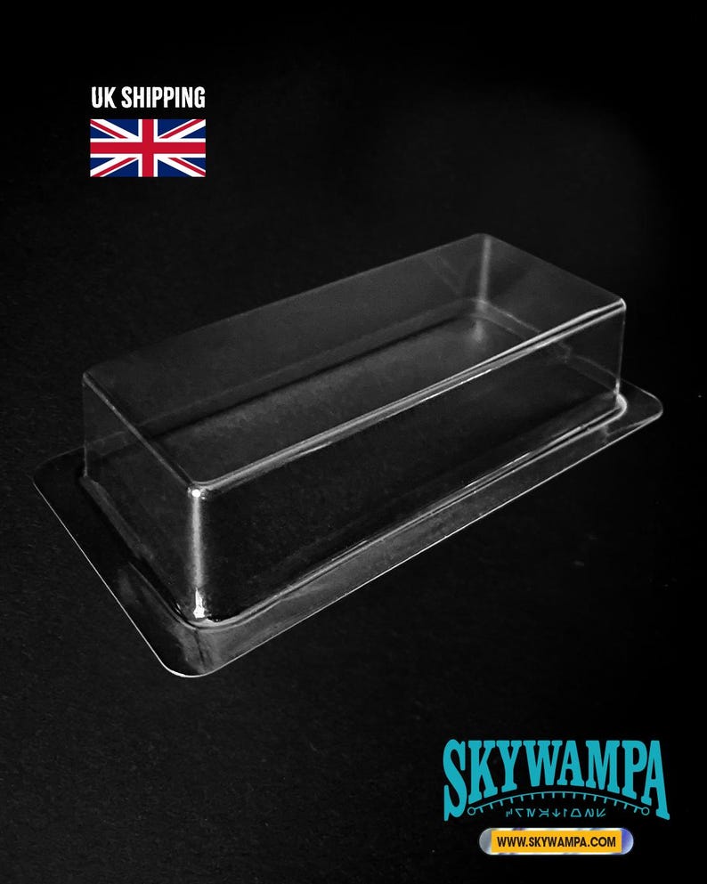 May include: A clear, rectangular plastic blister pack tray with a raised central cavity and a flat, wide border flange. The transparent container is designed for protective packaging and display, featuring a smooth, molded surface throughout.