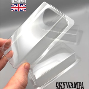 May include: A set of clear, rectangular plastic blister packaging trays with rounded corners and a raised central cavity. The transparent containers feature a smooth, molded design intended for protective storage or display of small items.