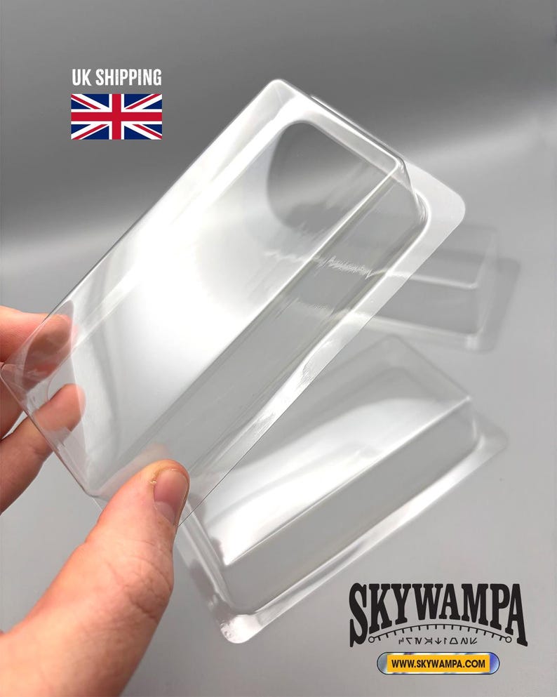 May include: A set of clear, rectangular plastic blister packaging trays with rounded corners and a raised central cavity. The transparent containers feature a smooth, molded design intended for protective storage or display of small items.
