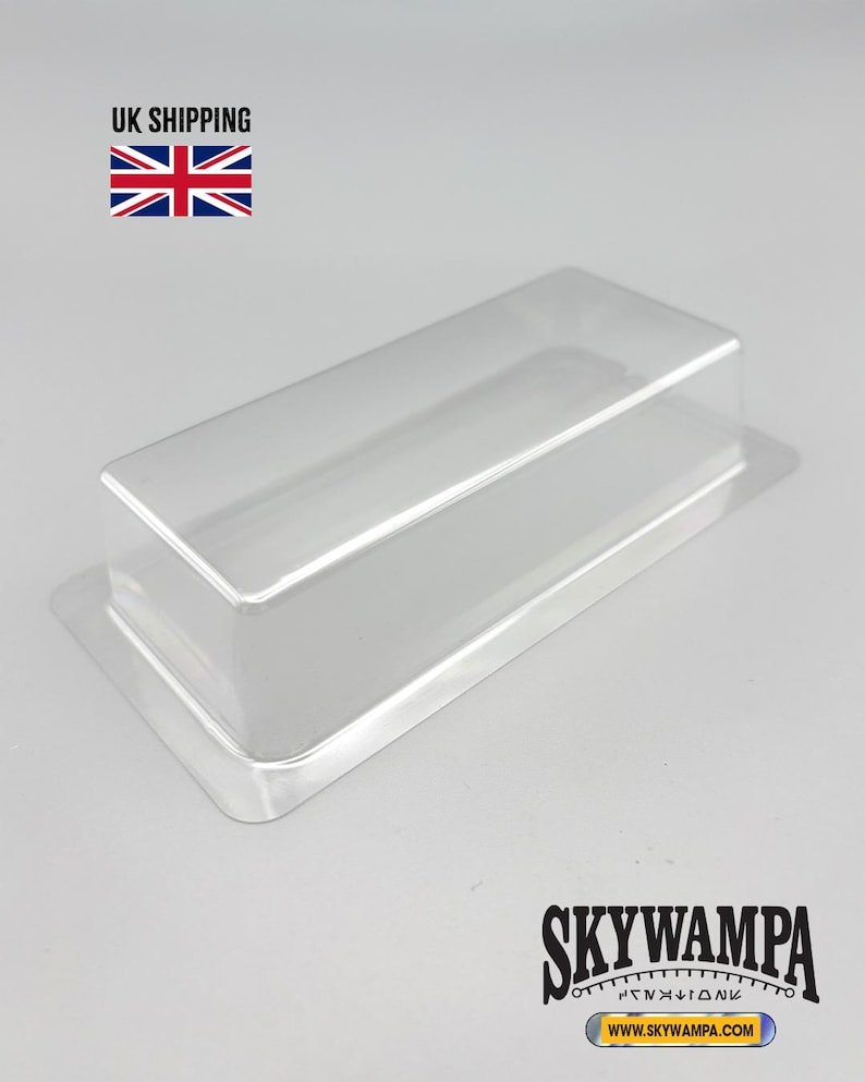 May include: A clear, rectangular plastic blister pack tray with a raised center section and a flat surrounding flange. The tray is transparent and molded into a simple box shape, designed for protective packaging of small items or collectibles.