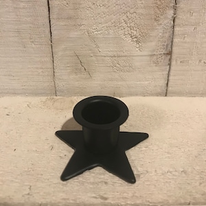 May include: Black metal candle holder shaped like a star with a round opening for a candle.