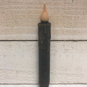 May include: A black taper candle with a faux wax drip effect and a light brown flame tip.