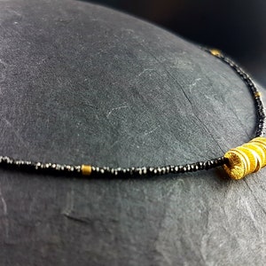 Thin very fine black spinel necklace with gold-plated elements sparkling and glittering