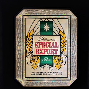 May include: A rectangular sign with the text "Heileman's SPECIAL EXPORT Beer". The sign has a white background with gold and green accents, and a star emblem. The text "YOU CAN TRAVEL THE WORLD OVER AND NEVER FIND A BETTER BEER" is also present.
