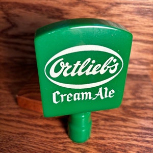 May include: Green plastic beer tap handle with a white oval logo that says "Oertlieb's Cream Ale".