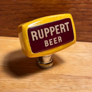 May include: Yellow beer tap handle with a red label that says "Ruppert Beer".