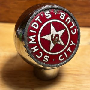 May include: A chrome beer tap handle with a red and white logo that says "Schmidts Club City" with a star and the letter "S" in the center.