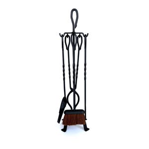 May include: Black wrought iron fireplace tool set. The set includes a poker, shovel, tongs, and a brush. The brush has a brown bristle head. The tools are suspended from a stand with a loop handle. The set is designed to stand on the floor.