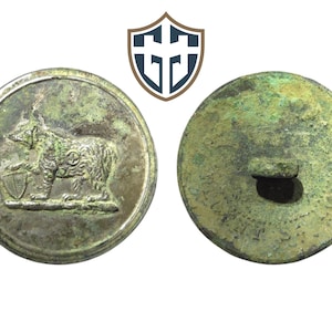 May include: A vintage metal button featuring a bear holding a shield on one side and a blank reverse with a hole for sewing on the other side.