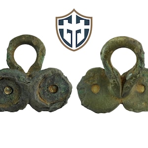 May include: A pair of antique bronze buckles with a loop and two round decorative elements. The buckles have a green patina and are in good condition.