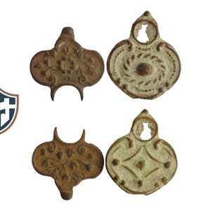 May include: Four antique bronze pendants. Two pendants feature floral designs, and two have geometric patterns. The pendants are in shades of brown and off-white, with a weathered appearance. Each has a hole at the top.