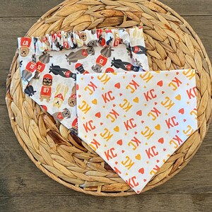K&ouml;nnte beinhalten: Zwei Hunde-Bandanas auf einer gewebten Matte. Ein Bandana hat einen wei&szlig;en Hintergrund mit sich wiederholenden Bildern von Hunden mit Football-Helmen und den Zahlen 15, 51 und 87. Das andere Bandana hat einen wei&szlig;en Hintergrund mit sich wiederholenden "KC"- und Herzmustern.