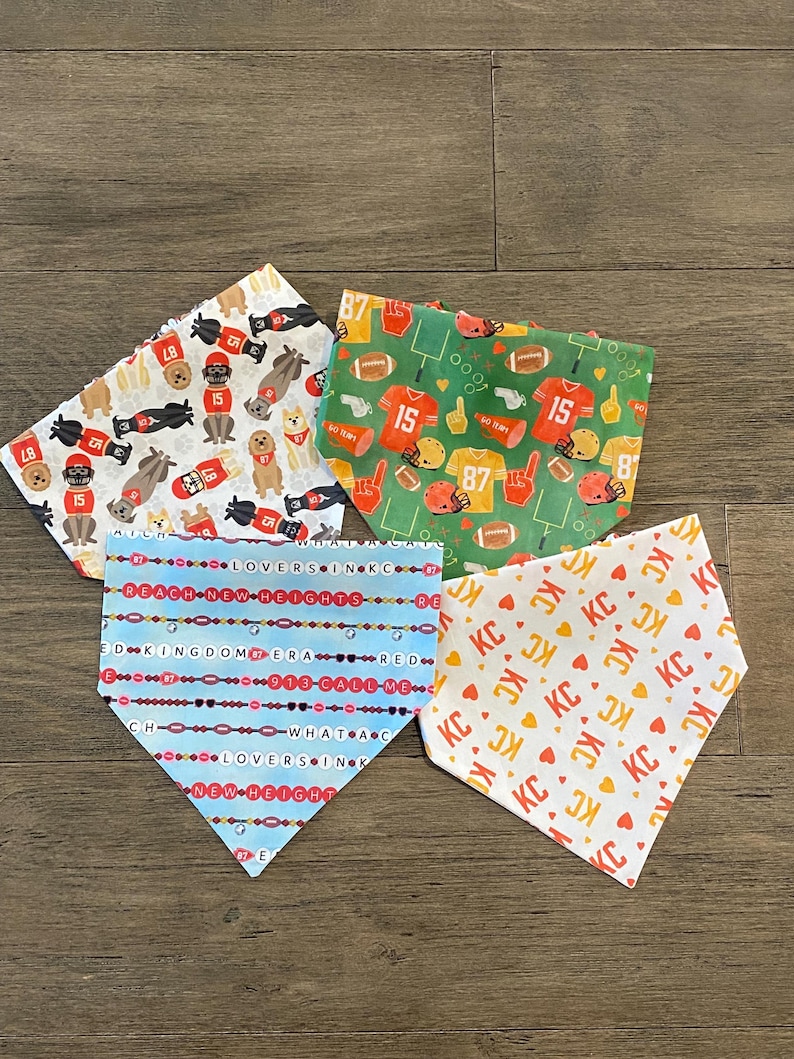 K&ouml;nnte beinhalten: Vier Hunde-Bandanas mit verschiedenen Mustern. Eines zeigt Football-Motive mit den Nummern 15 und 87. Ein anderes hat ein sich wiederholendes "KC"-Muster. Das dritte hat den Text "LOVERS IN KC" und "REACH NEW HEIGHTS". Das letzte hat Hunde und Fu&szlig;b&auml;lle.
