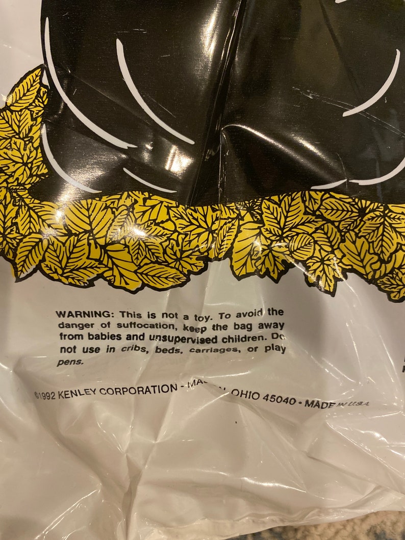 May include: A white plastic bag with a black graphic design and yellow leaf accents. The bag has a warning label with text about suffocation hazards and the text "&copy;1992 KENLEY CORPORATION - MA OHIO 45040 - MADE IN USA."