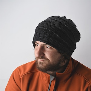 May include: A man wearing a black knit beanie and an orange fleece jacket.