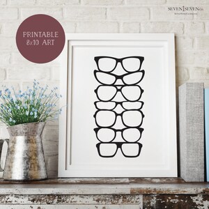 Op de afbeelding: Zwart-witte printbare kunstprint van een stapel van zes verschillende brillen. De print is 8x10 inch en is ingelijst in een wit frame.