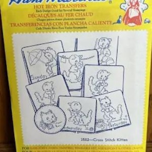 May include: A yellow box of Aunt Martha's Hot Iron Transfers featuring cross-stitch kitten designs. The box includes multiple transfer sheets with kitten illustrations, labeled with days of the week. The text "3502-Cross Stitch Kitten" is visible.