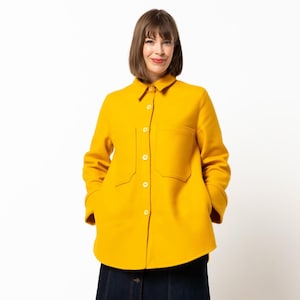 Może przedstawiać: Jasnożółta koszulo-kurtka z dwiema przednimi kieszeniami i białymi guzikami. Kurtka jest połączona z ciemnoniebieską dżinsową spódnicą. Strój jest noszony przez osobę z krótkimi brązowymi włosami.