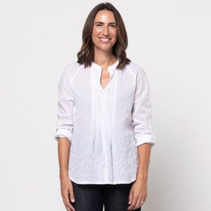 May include: A white, long-sleeved button-down shirt with a pleated front and a v-neck collar. The shirt is made of a lightweight fabric and has a relaxed fit.