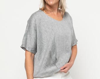 May include: A gray linen top with a relaxed fit and short sleeves. The top has a slightly textured surface and a round neckline.