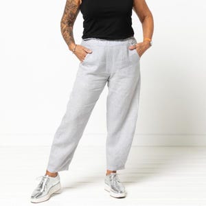 Könnte beinhalten: Graue Leinenhose mit weitem Bein und Kordelzugbund. Die Hose hat zwei Eingrifftaschen und zwei Gesäßtaschen.