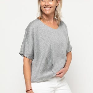 May include: A gray linen top with a relaxed fit and short sleeves. The top has a slightly textured surface and a round neckline.